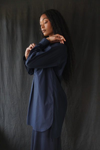 Side view of model wearing The Tunica Operis shirt in Navy.